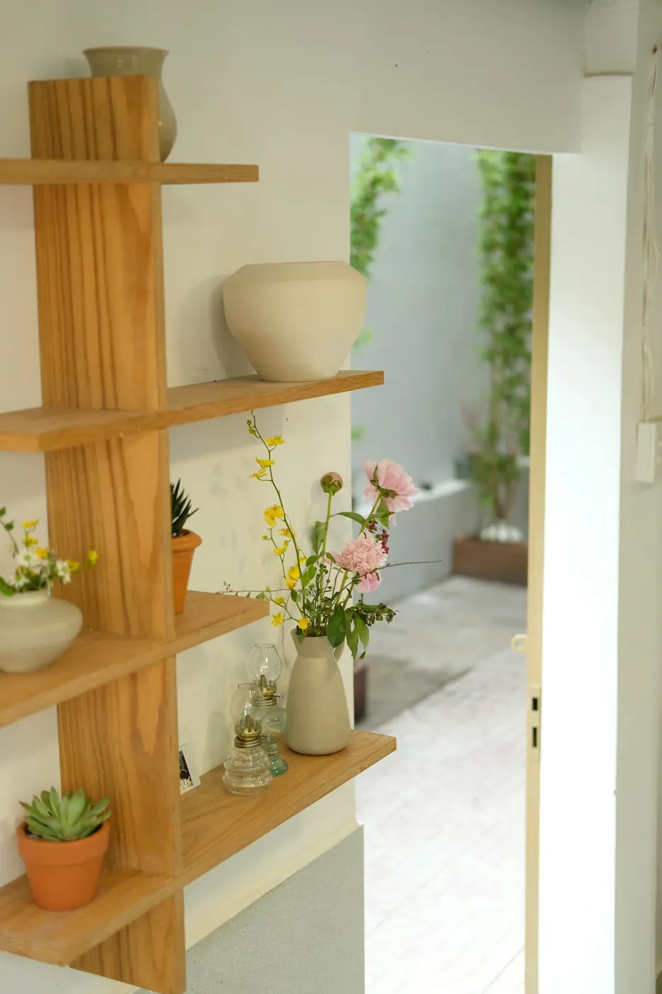 Étagère en bois garnie de vases et de petites compositions florales