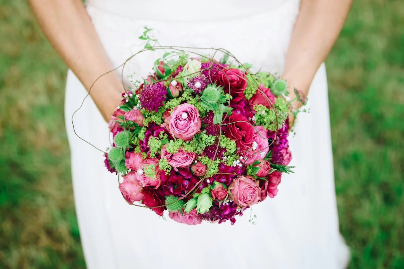 Mariée tenant un bouquet aux tons framboise